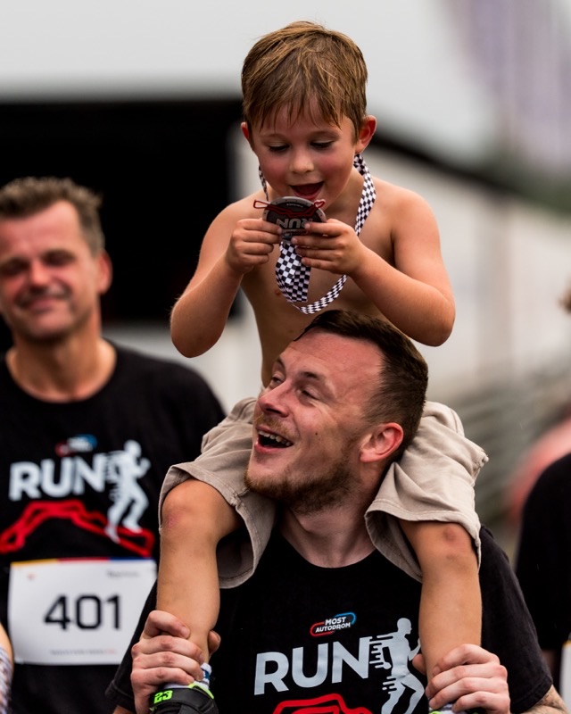 Child on man's shoulders holding a finisher medal